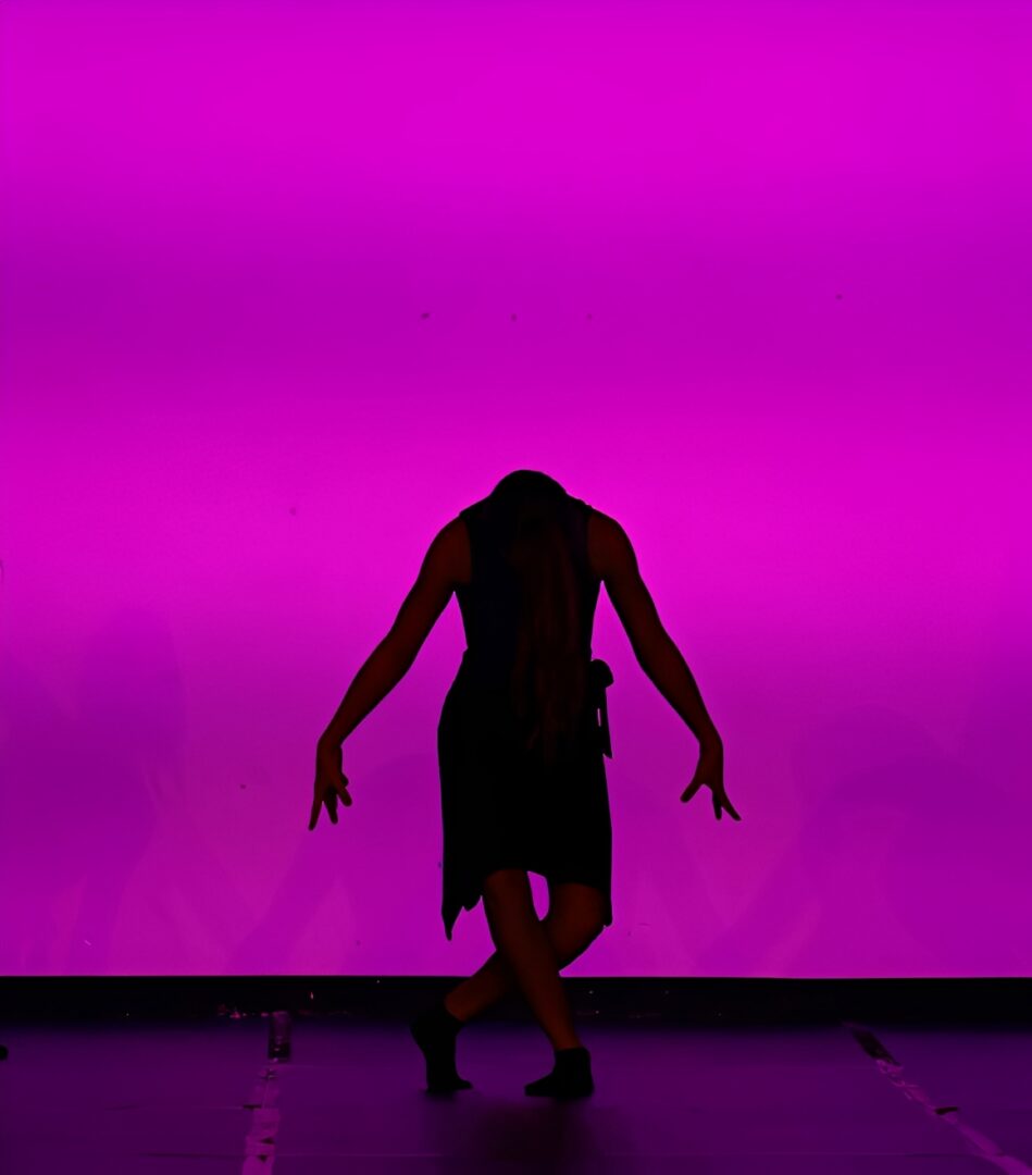 Silhouette of dancer against purple background.