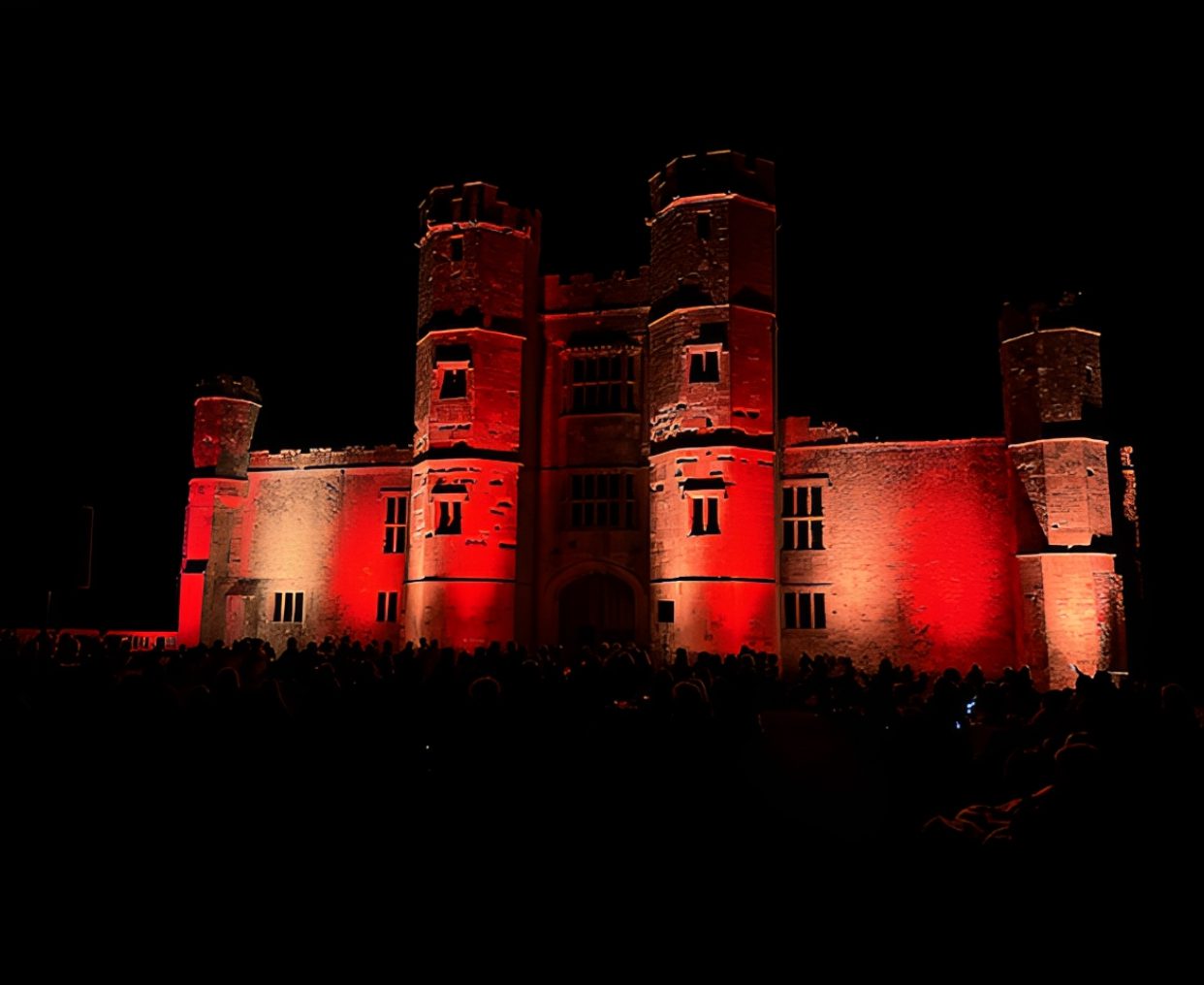 Castle illuminated with red lights at night.