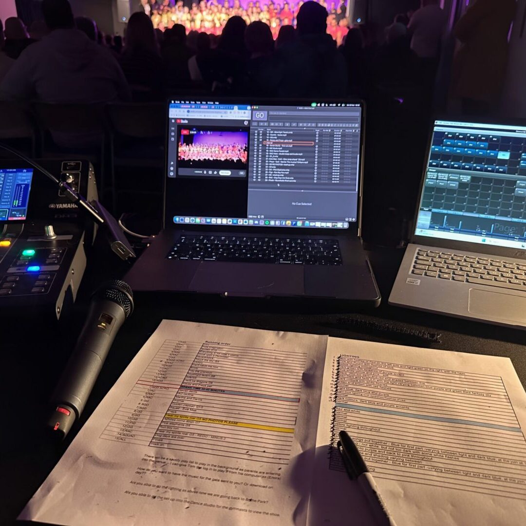 Concert audio setup with laptops and microphone.